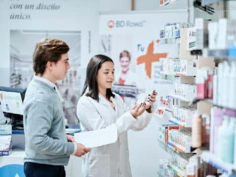 Una alumna CEU atendiendo a un cliente en la farmacia