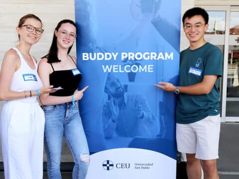 Tres alumnos posando junto a un roll up en el budy Fest celebrado en el campus de Montepríncipe