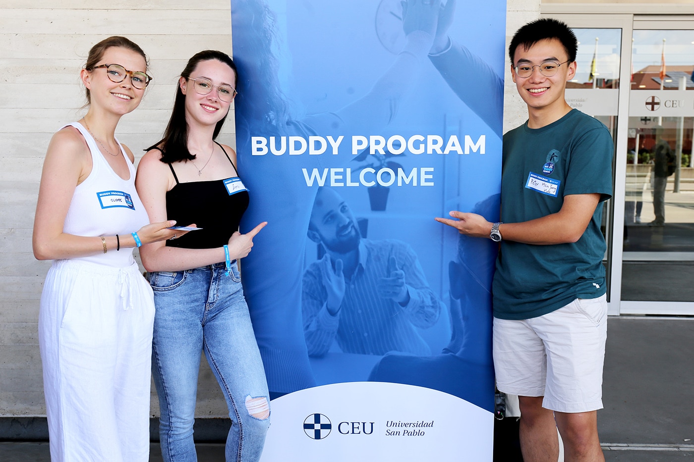 Tres alumnos posando junto a un roll up en el budy Fest celebrado en el campus de Montepríncipe